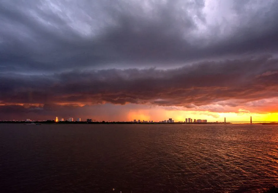 A city skyline under a dramatic stormy sky with a vibrant sunset provides a powerful contrast.