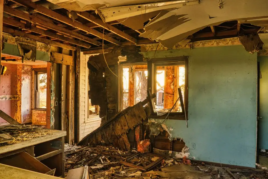 A view of a severely damaged room in an abandoned home, showcasing destruction and rubble.